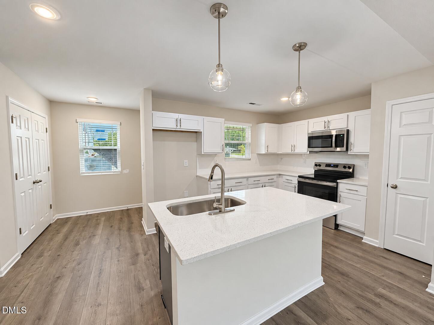 Kitchen with a large white island, undermount sink, white cabinets, and stainless steel appliances.