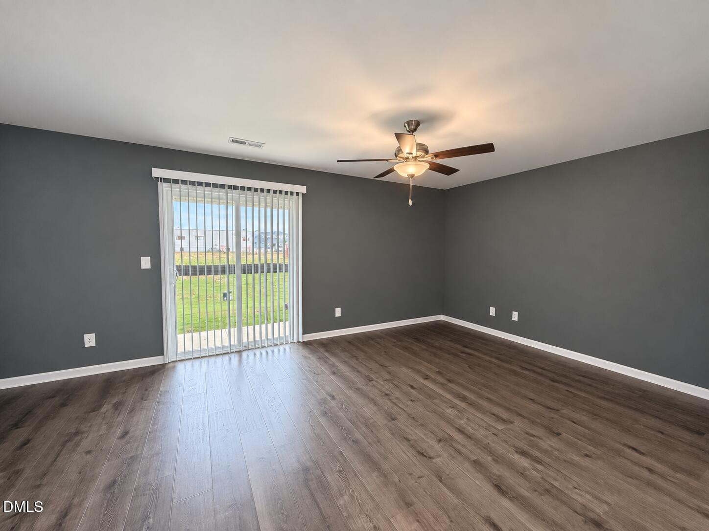 Vacant living room with wood-look floors, gray walls, and a sliding glass door.