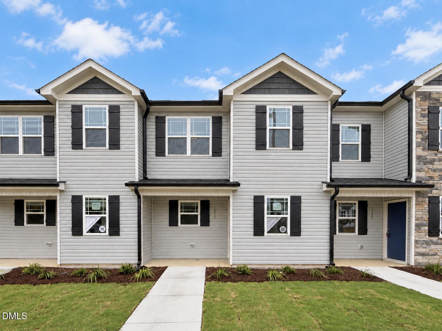 Front exterior of 1205 Brookrun Drive in Oxford, NC, featuring light gray siding, black shutters, gabled rooflines, and a covered porch.