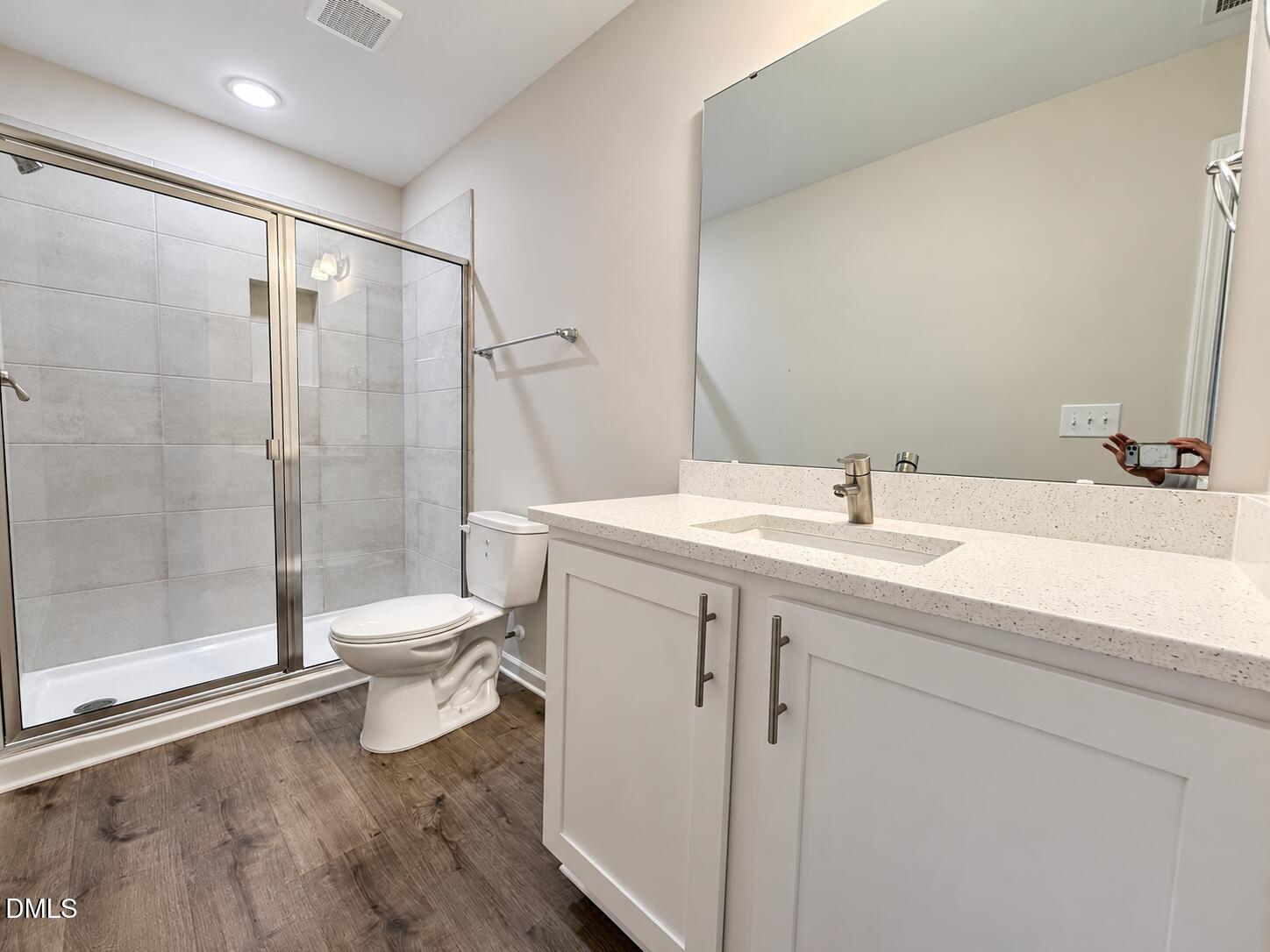 Modern bathroom with a glass-enclosed tiled shower and white vanity.