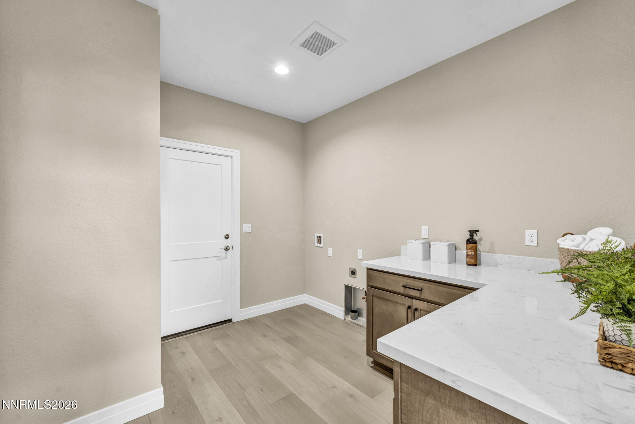 Laundry room with white countertop, brown cabinets, and washer hookups.