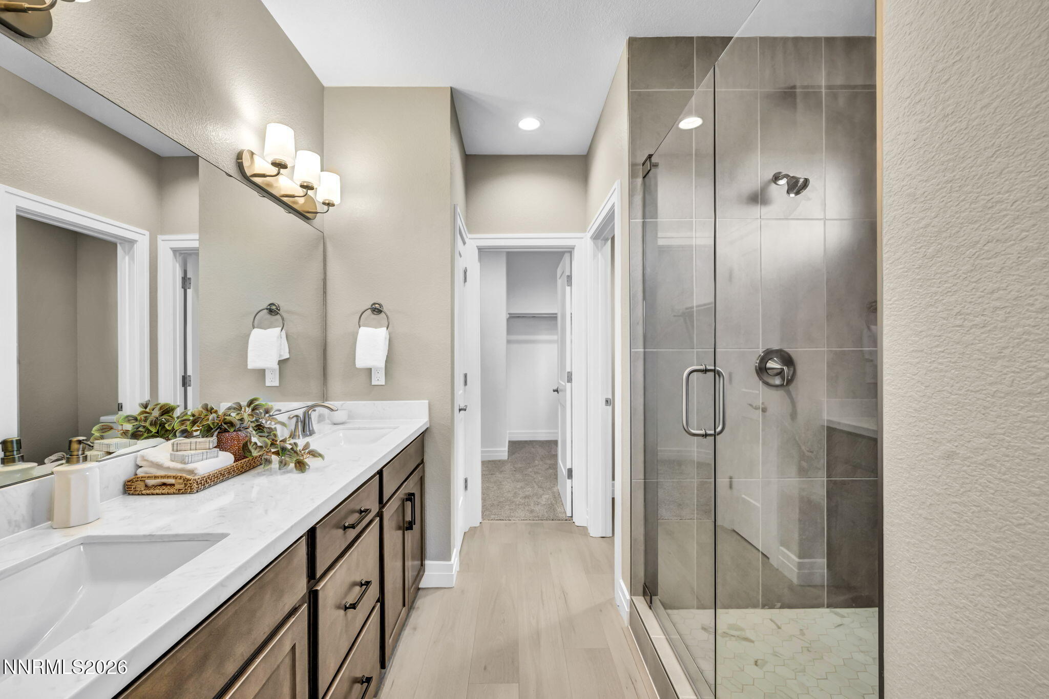 Bathroom with a long double-sink vanity and a glass-enclosed gray-tile shower.