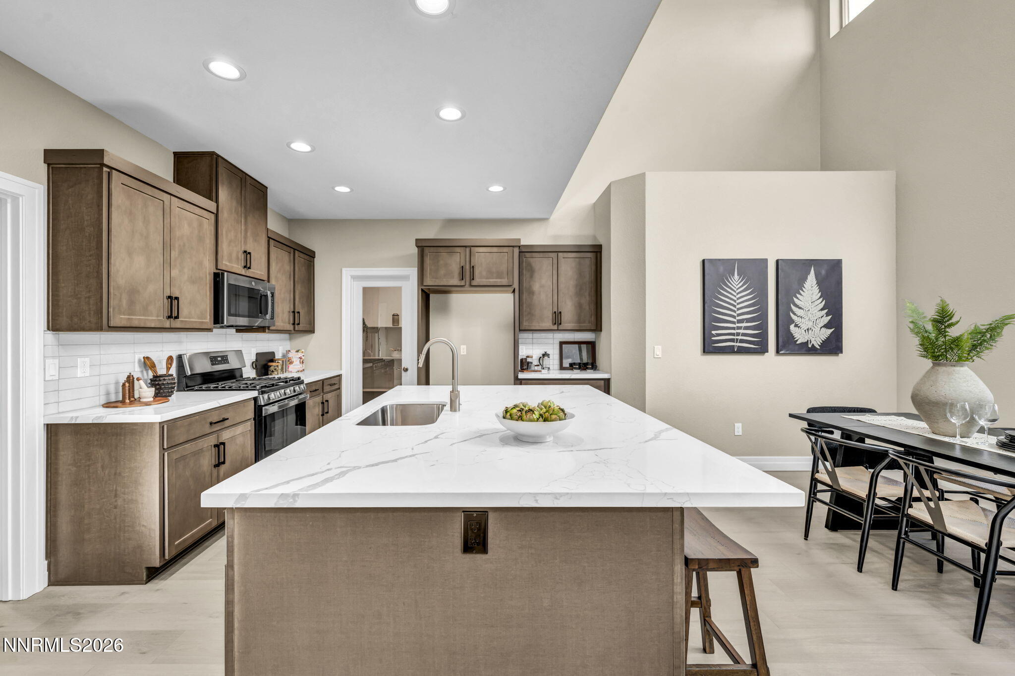 Kitchen with dark wood cabinets, stainless steel appliances, and a large white island with a sink.
