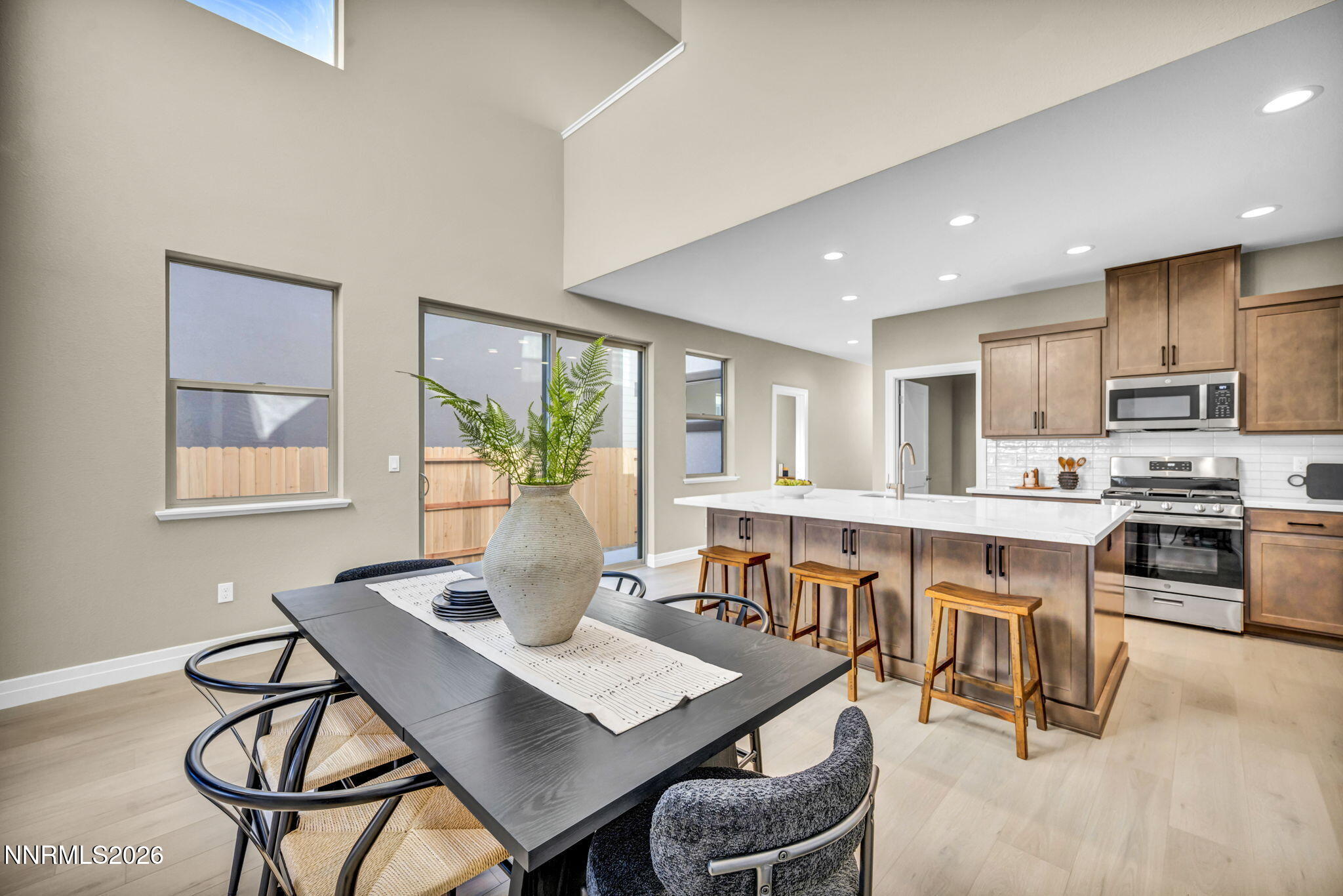 Open-plan kitchen and dining area with a large island, wood cabinetry, and a dark dining table.