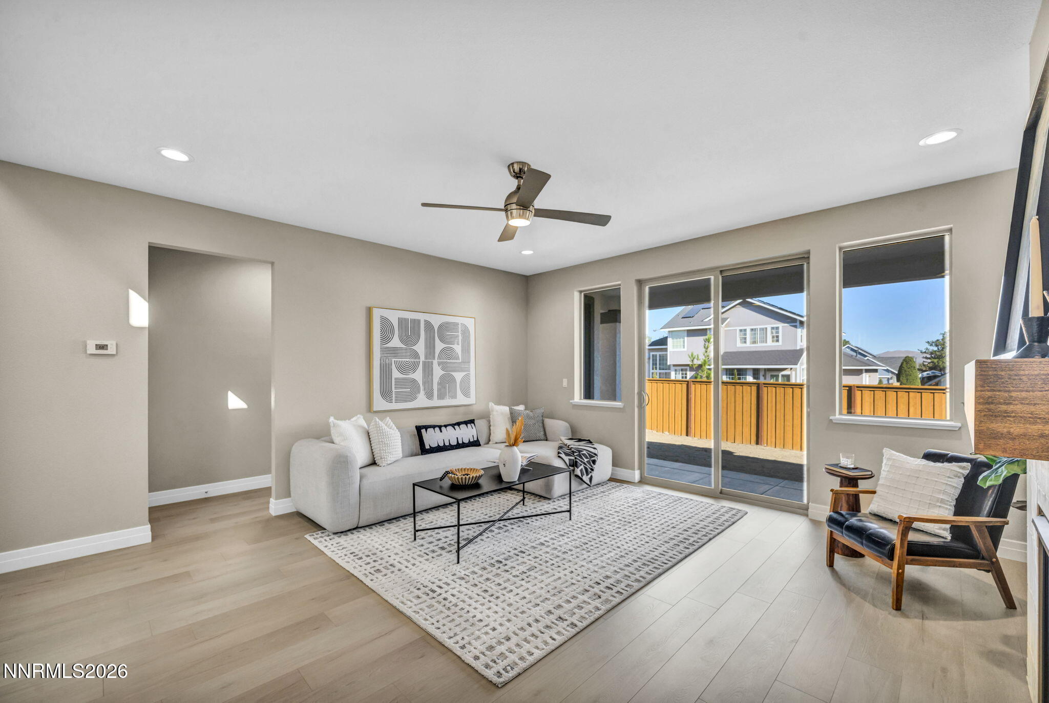 Staged living room with a white sectional, patterned rug, and sliding doors to a fenced patio.