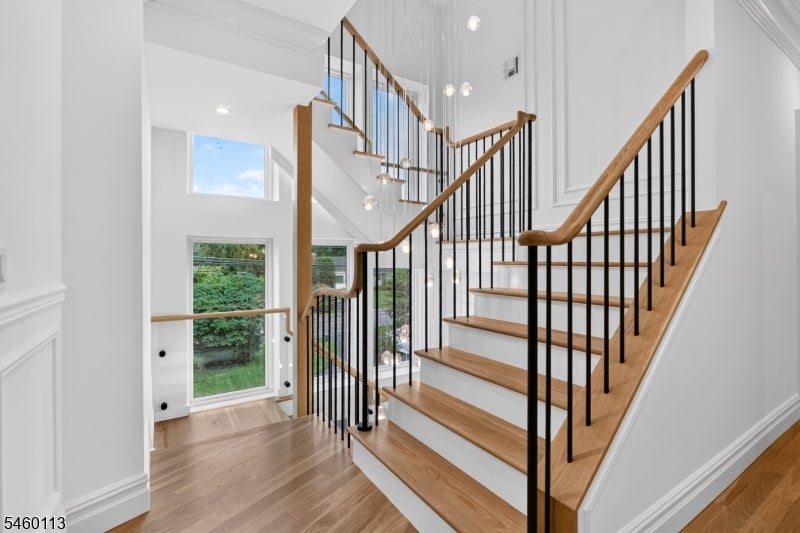Two-story staircase with wood treads, black balusters, pendant lights, and tall windows.