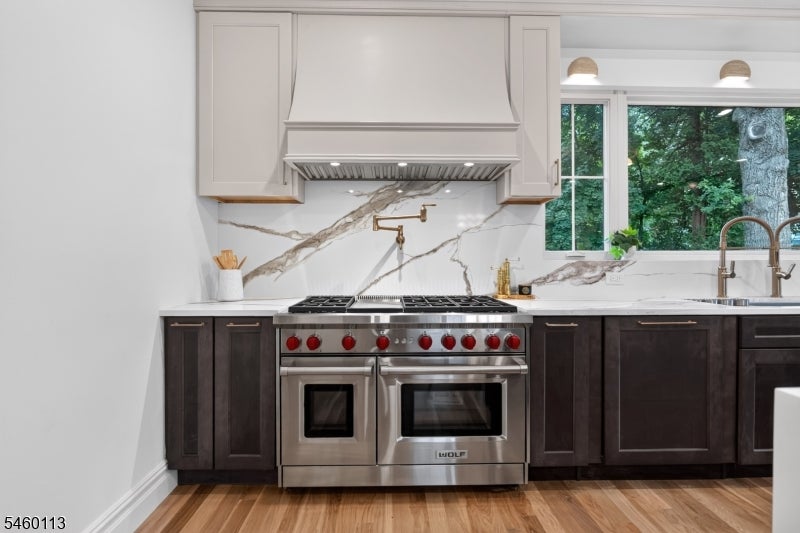 Kitchen with a stainless double-oven range, veined marble backsplash, and dark lower cabinets.