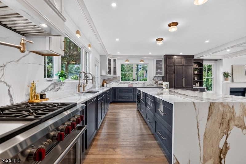 Renovated kitchen with navy cabinets, marble counters, a large island, and stainless steel range.