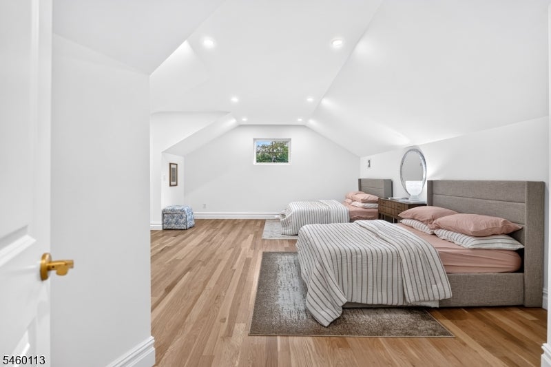 Attic bedroom with two beds, sloped ceilings, and hardwood flooring.