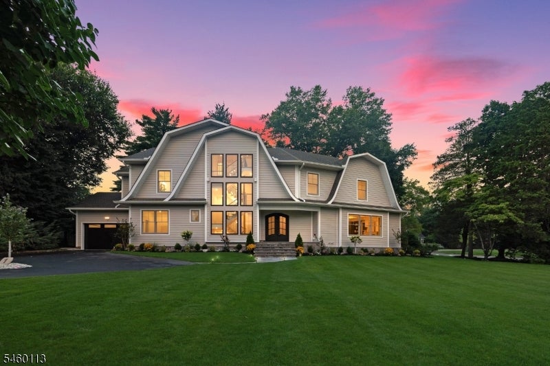 Gray two-story house with tall central windows and a wide lawn beneath a pink dusk sky.