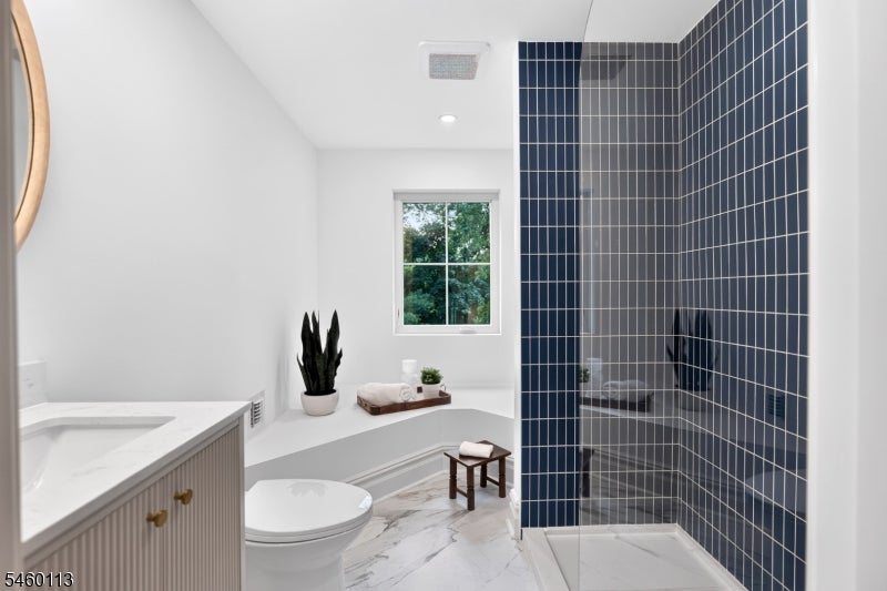 Modern bathroom with a dark blue tiled glass shower and white vanity.