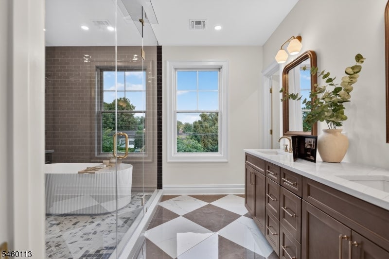 Bathroom with glass shower, freestanding tub, dark wood vanity, and diamond-pattern tile floor.