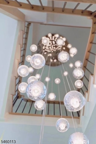 Stairwell with wooden railings and a large hanging chandelier.