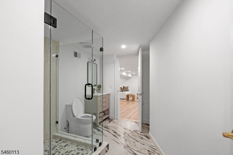 Bathroom with glass-enclosed shower, marble-patterned floor, and a view into an adjoining sitting room.