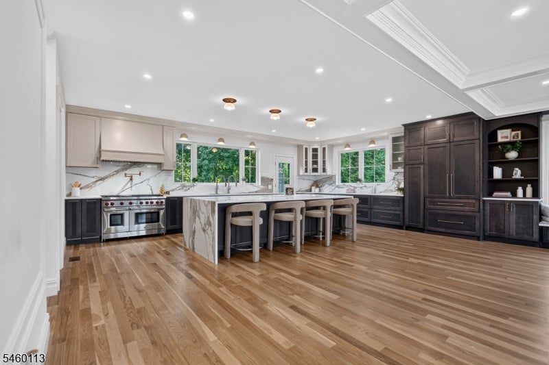 Spacious kitchen with a marble island, bar stools, dark cabinetry, and hardwood floors.