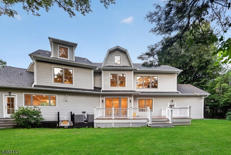 Rear of a gray two-story home with white-railed decks and a broad green lawn.
