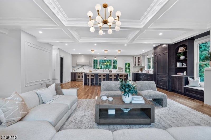 Open-plan living room and kitchen with a large island, dark cabinetry, and coffered ceiling.
