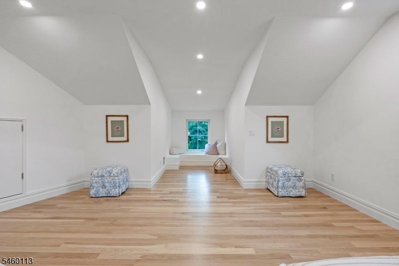 Finished upper-level room with light hardwood floors, recessed lights, and a cushioned window nook.