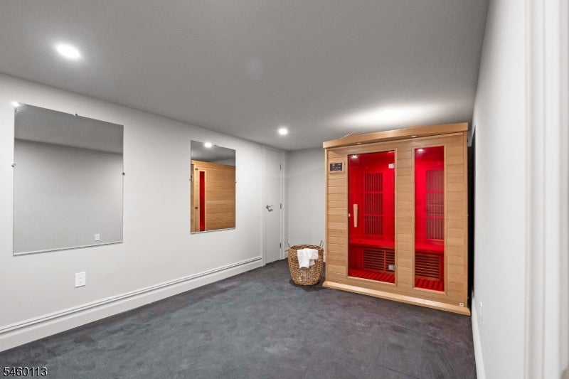 Interior room with a red-lit infrared sauna and mirrored wall panels.