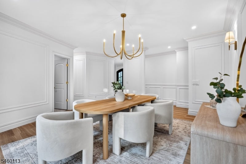 Dining room with a long wood table, upholstered chairs, and a brass chandelier.