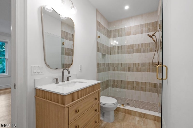 Bathroom with a wood vanity and glass shower featuring striped beige and gray tile.