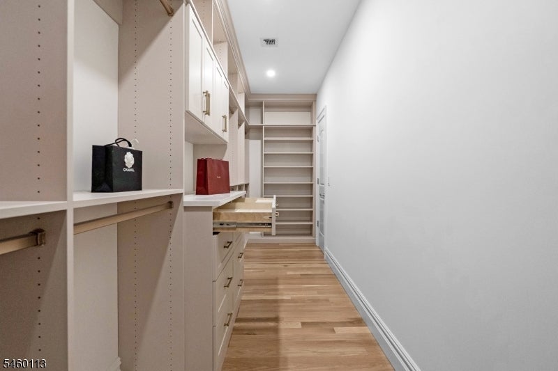 Walk-in closet with built-in shelving, drawers, and two shopping bags.