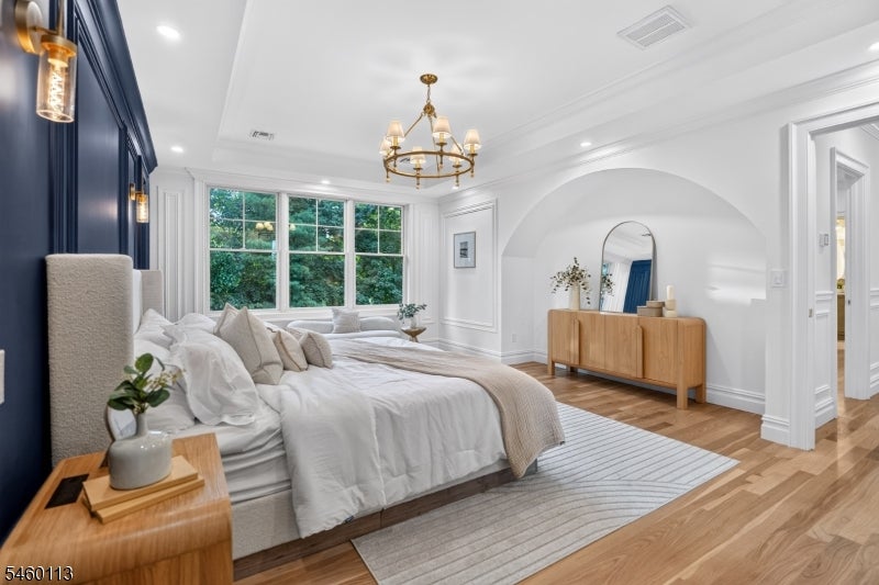 Staged bedroom with a navy paneled wall, large garden-facing windows, and an arched alcove.