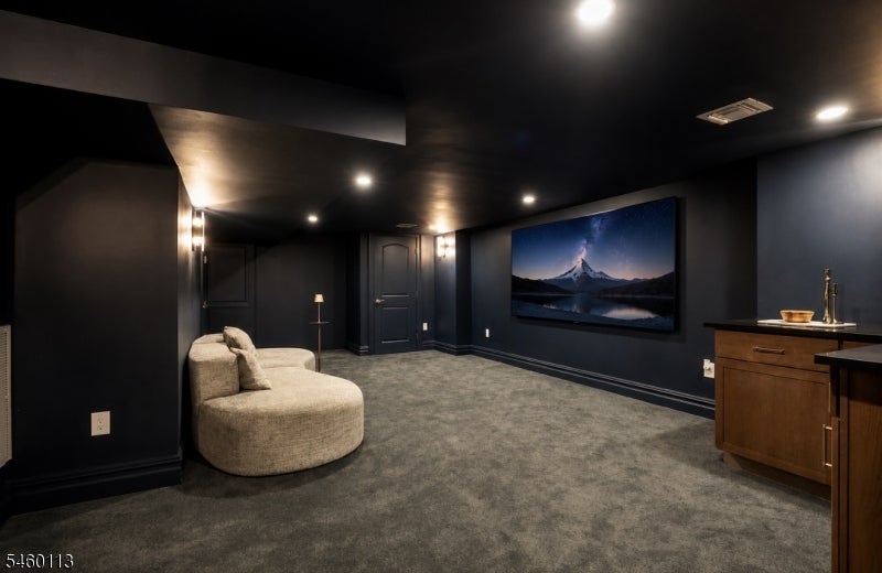 Basement media room with a curved cream sofa, large wall-mounted screen, and wooden wet bar.