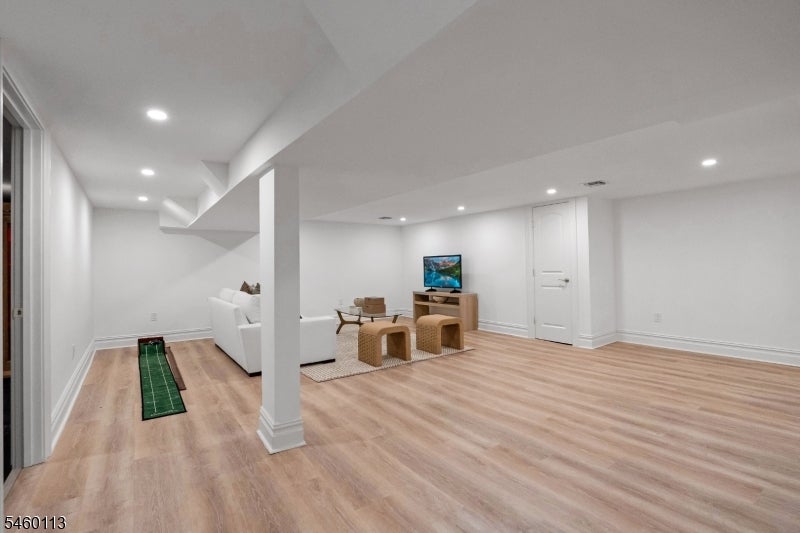 Finished basement recreation room with wicker seating and a narrow putting mat.