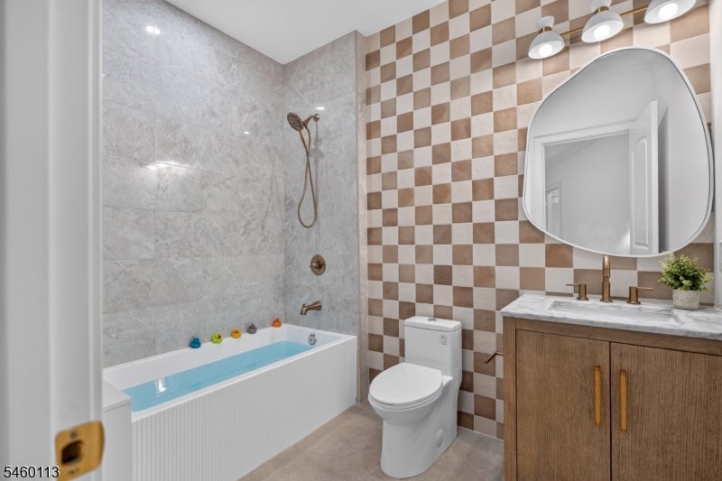 Bathroom with a bathtub and shower, checkerboard tile accent wall, and wood vanity.