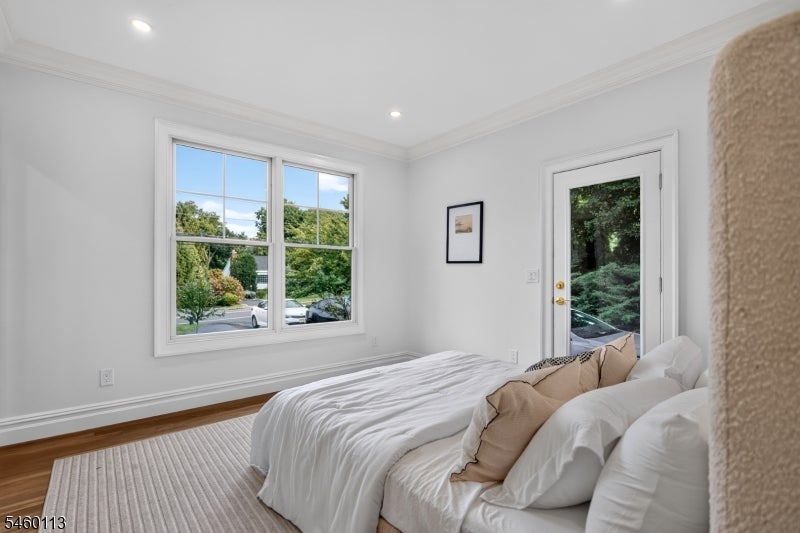 Bright bedroom with a white bed, large divided-pane window, and glass door facing greenery.