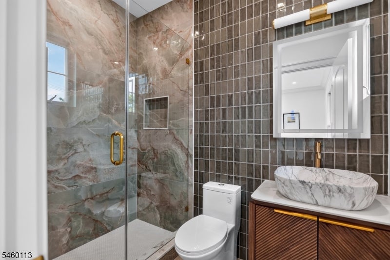 Bathroom with a stone-look glass shower, marble vessel sink, and dark wood vanity.