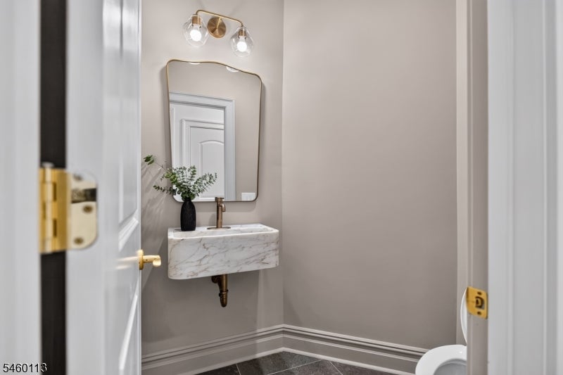 Powder room with a floating marble sink, brass fixtures, and a rounded mirror.