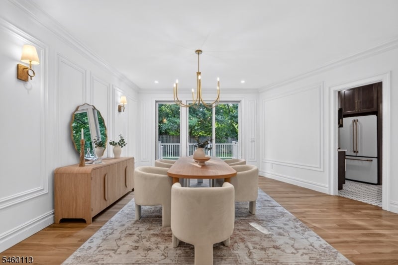 Dining room with a wood table, cream upholstered chairs, white paneled walls, and sliding doors to greenery.