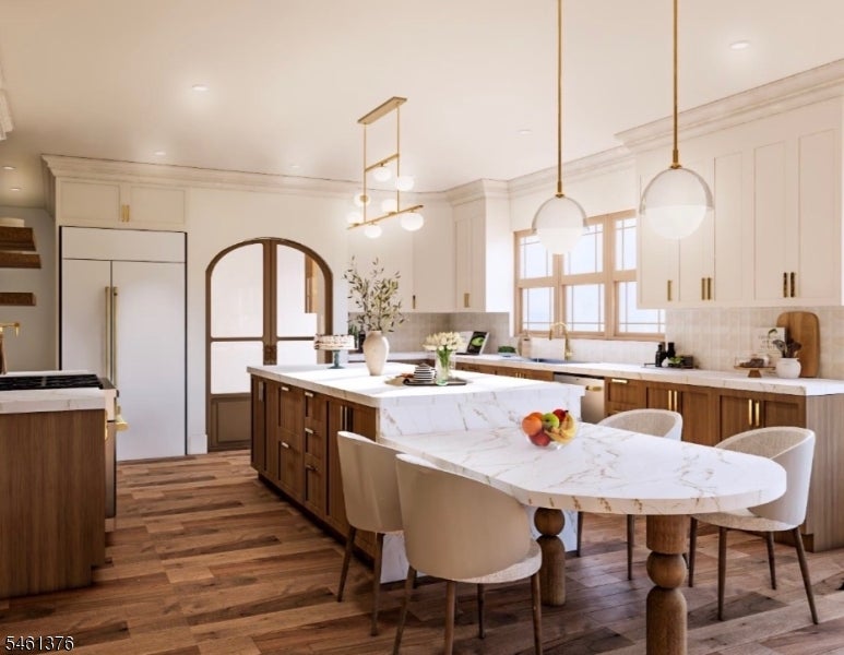 Kitchen with a large marble island and dining table, white cabinets, and warm wood finishes.