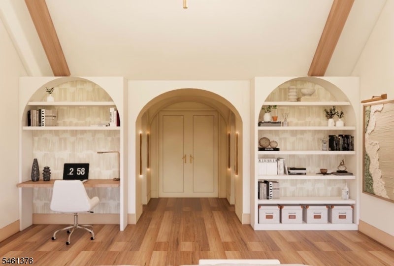 Home office with arched built-in bookcases, a central arched doorway, and hardwood floors.