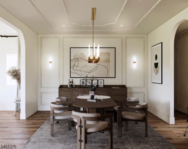Dining room with a dark wood table, upholstered chairs, paneled walls, and a modern chandelier.