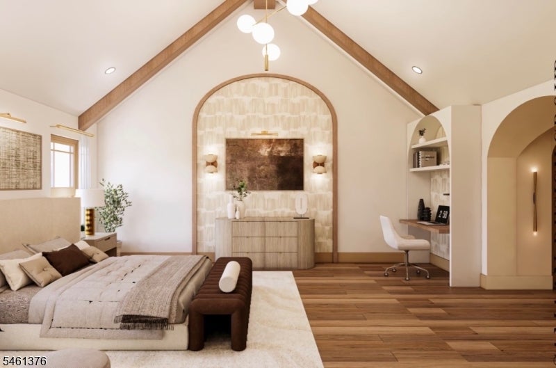 Bedroom with a vaulted wood-beamed ceiling, arched feature wall, and built-in desk.