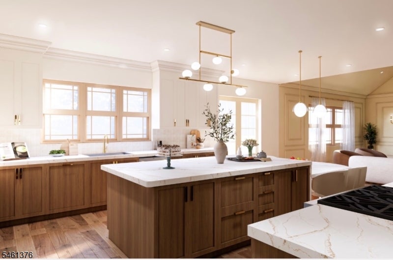 Bright kitchen with warm wood cabinetry, a large marble island, and pendant lighting.