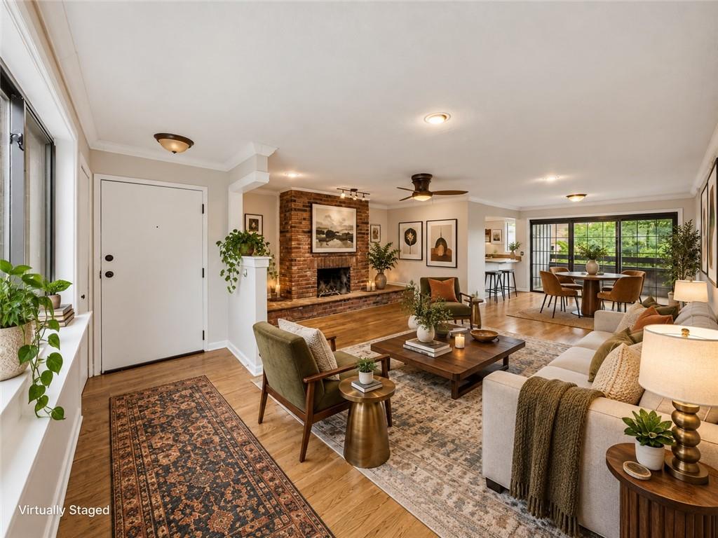 Virtually staged living room with a brick fireplace, hardwood floors, and an adjoining dining area.
