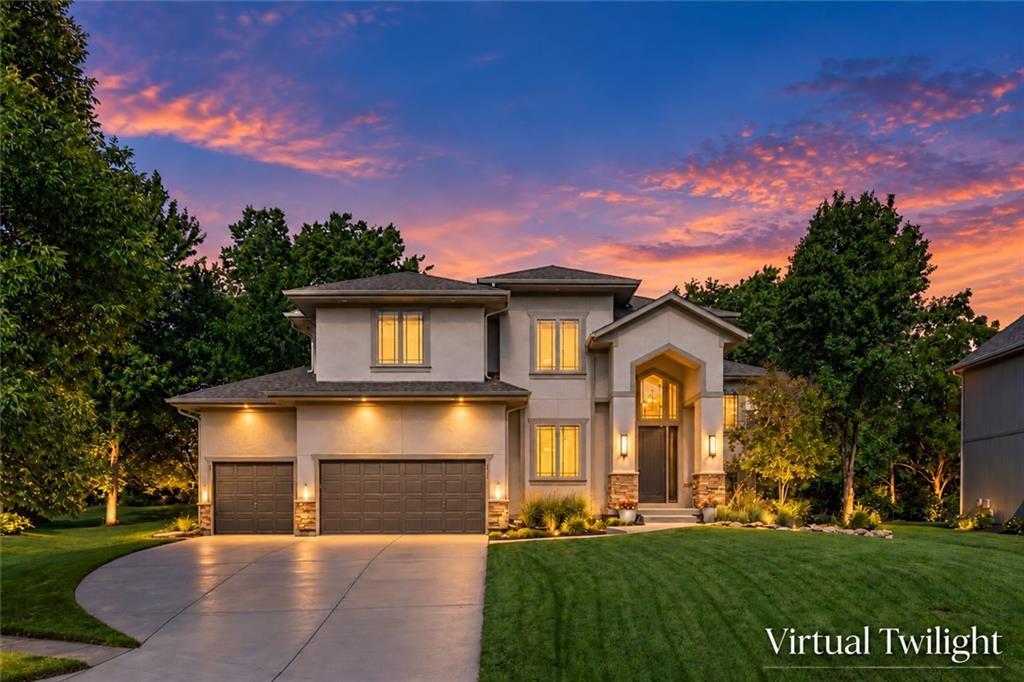 Two-story stucco home with a double garage and curved driveway at sunset.