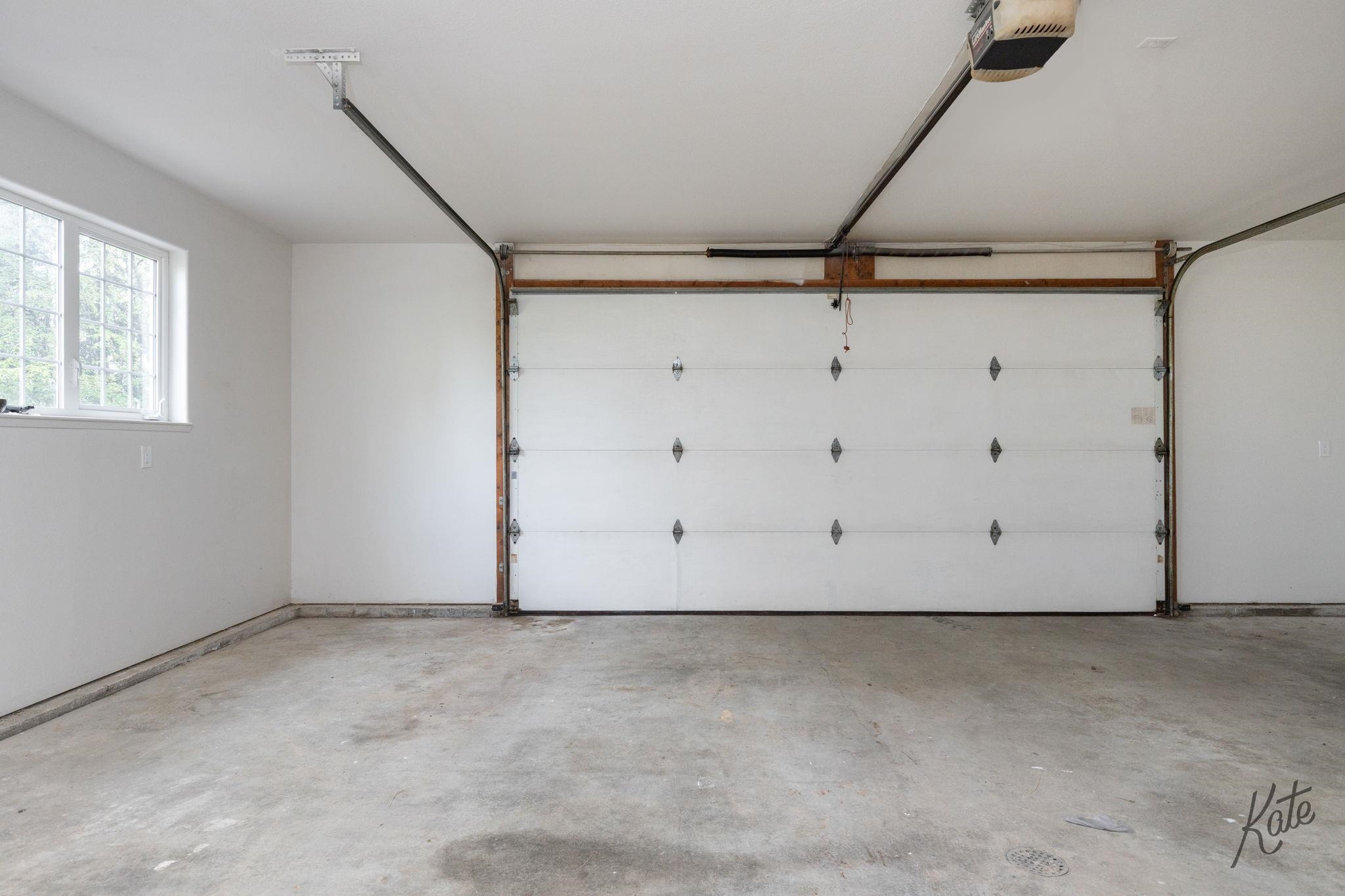 Empty garage with a concrete floor, closed overhead door, and side window.