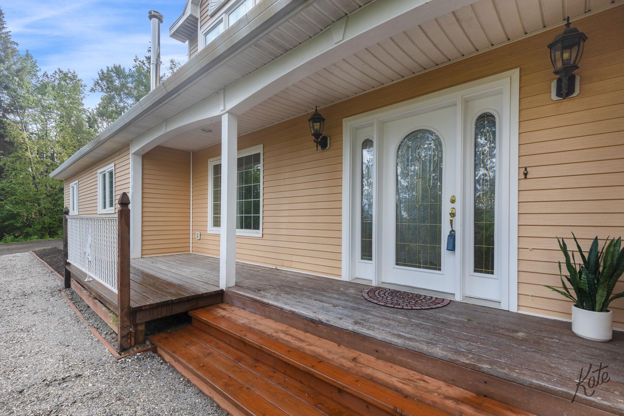Covered front porch with wooden steps and a white decorative-glass entry door.