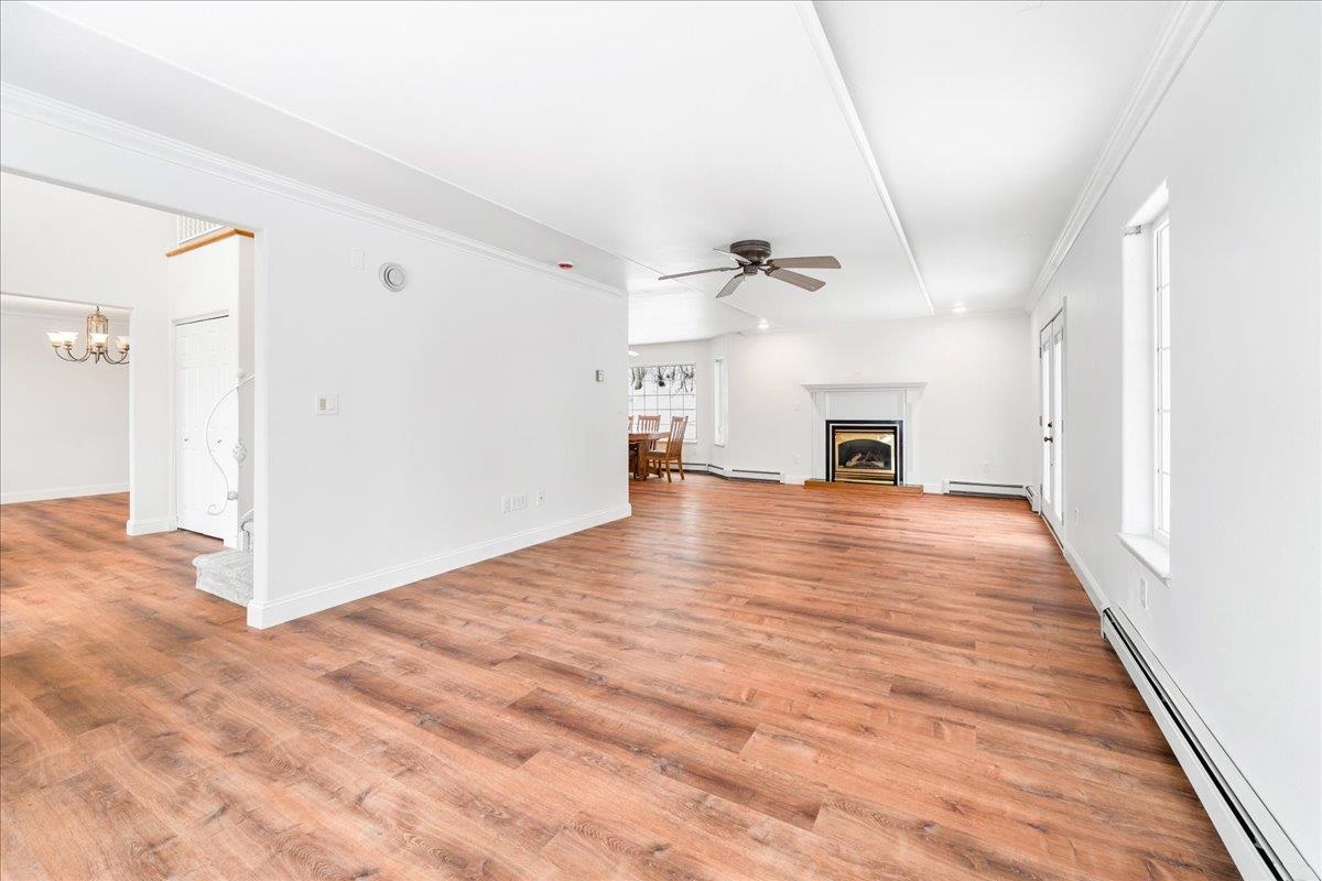 Open living room with wood flooring, a fireplace, and an adjoining dining area.