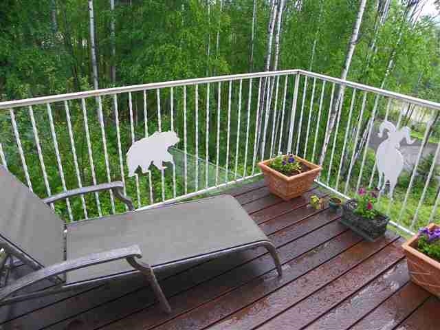 Deck with a reclining chair and flower planters overlooking dense green trees.