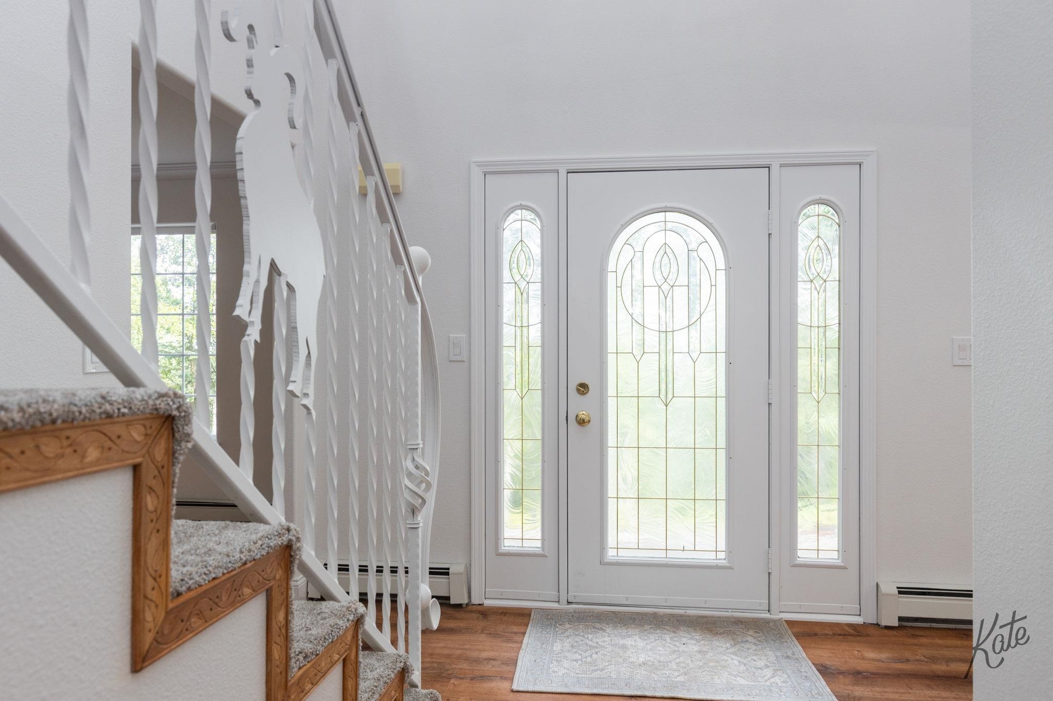 Entryway with a decorative glass front door, matching sidelights, and a carpeted staircase.