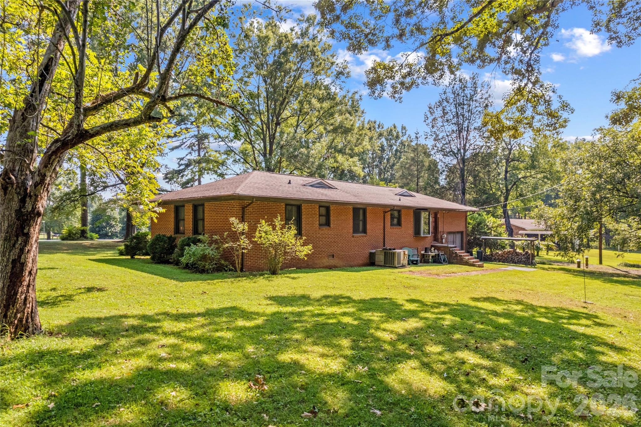 Brick ranch home with a broad lawn and mature trees.