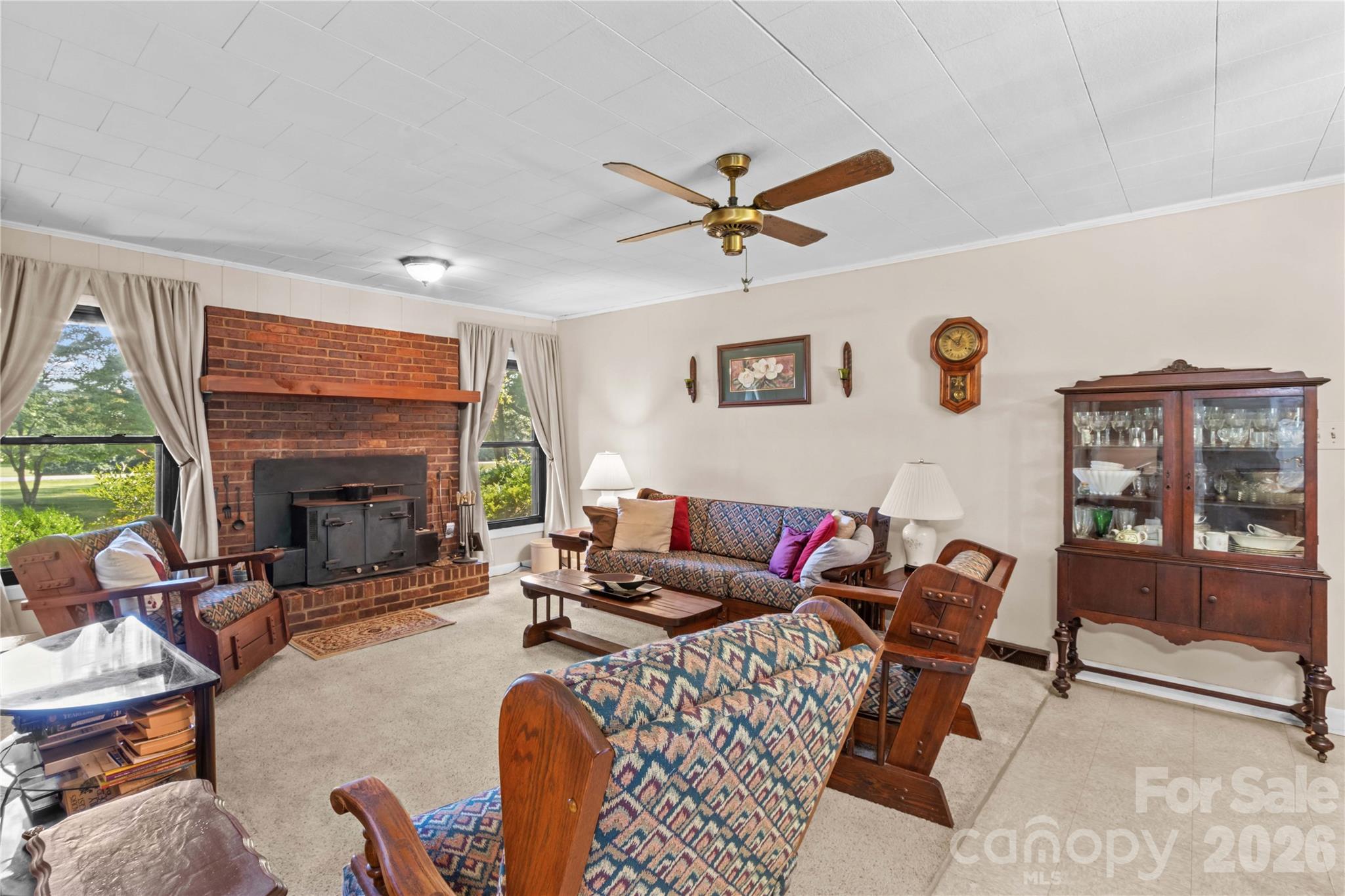 Furnished living room with a brick fireplace, wood stove, and patterned seating.