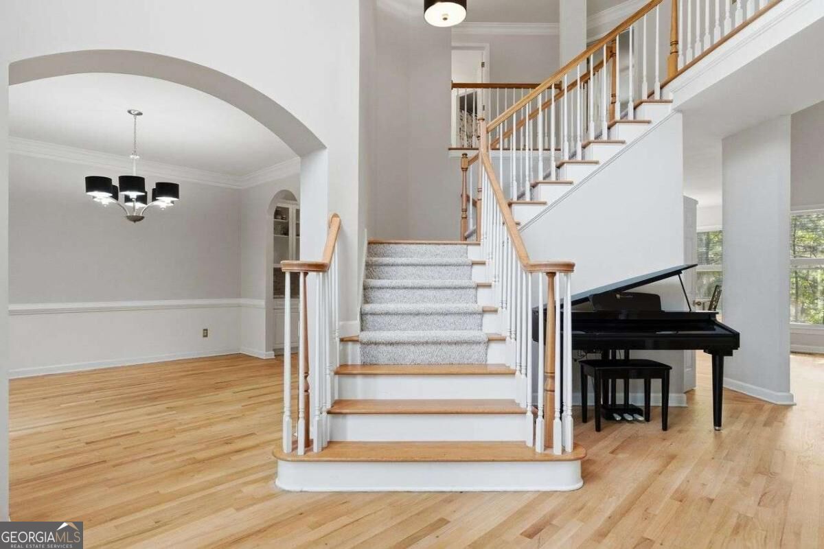 Two-story foyer with a carpeted staircase, hardwood floors, and a black grand piano.
