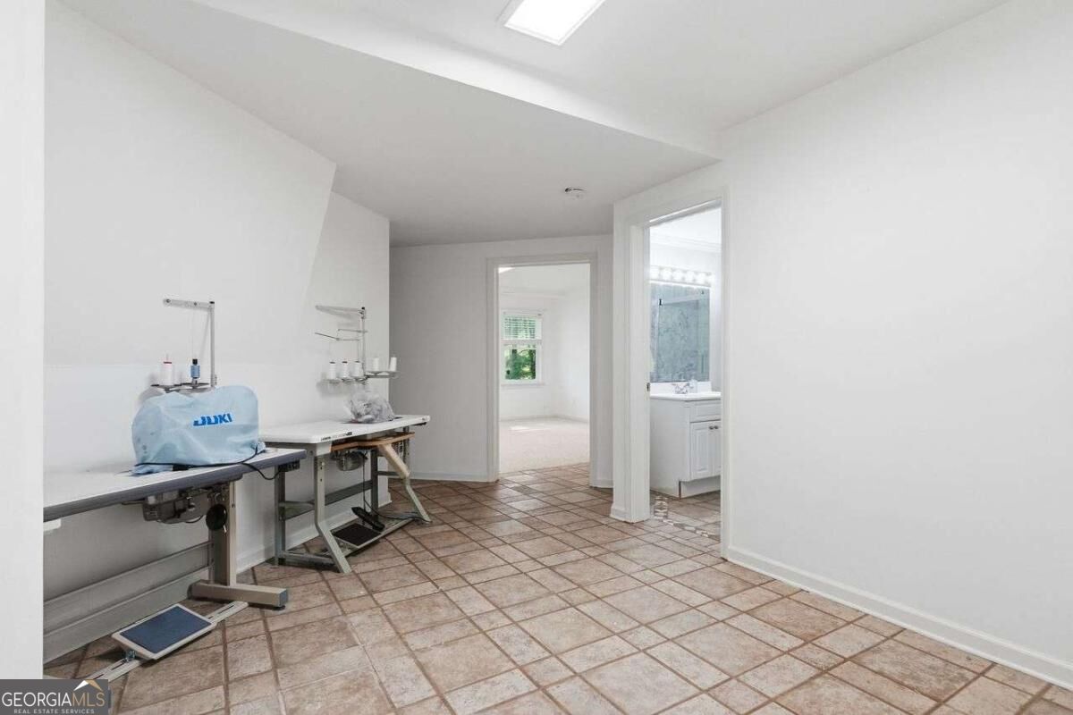 Sewing room with industrial machines, tiled floor, and an adjoining bathroom doorway.